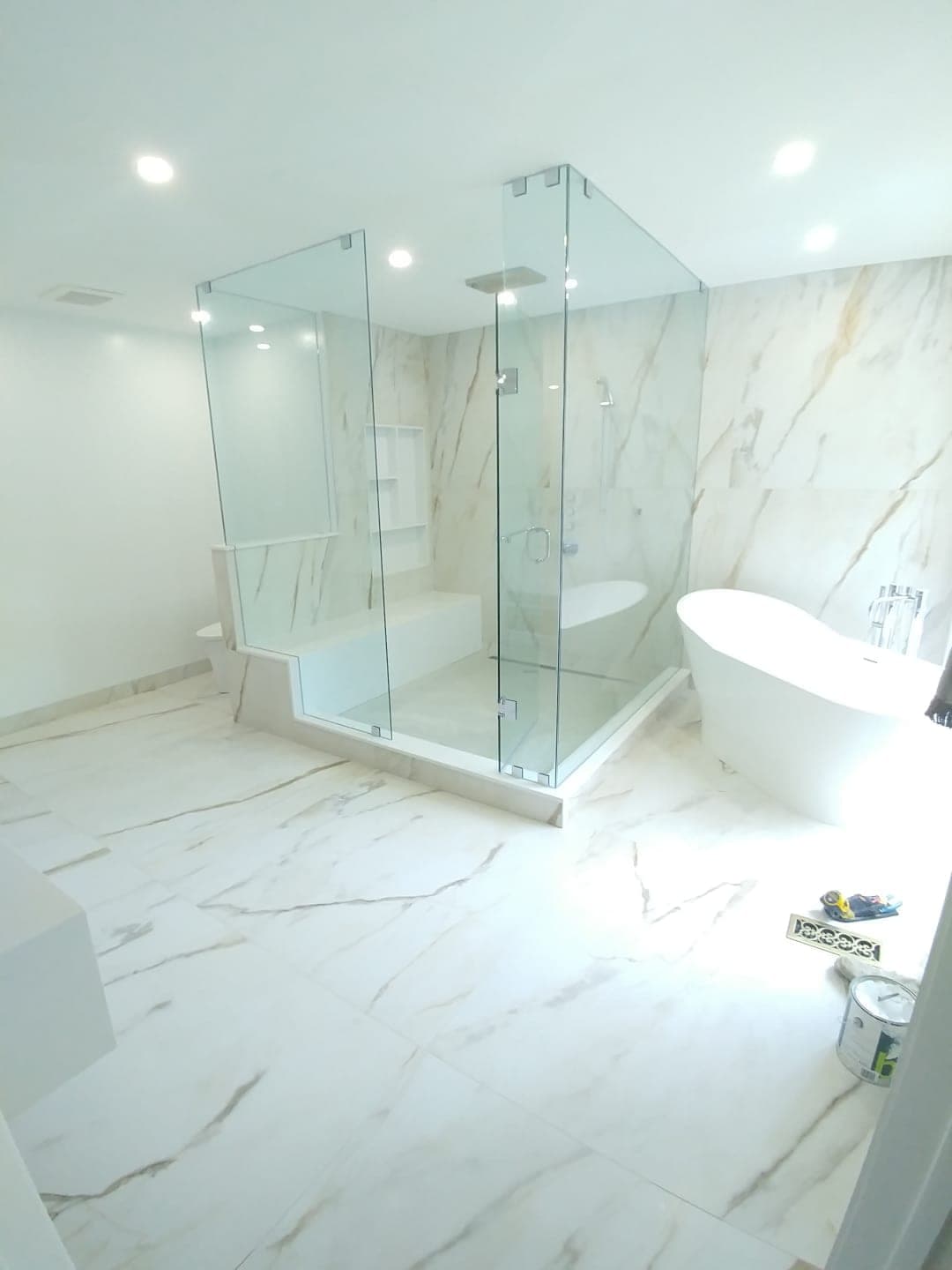 Marble bathroom renovation with frameless glass shower enclosure and freestanding tub in Vaughan